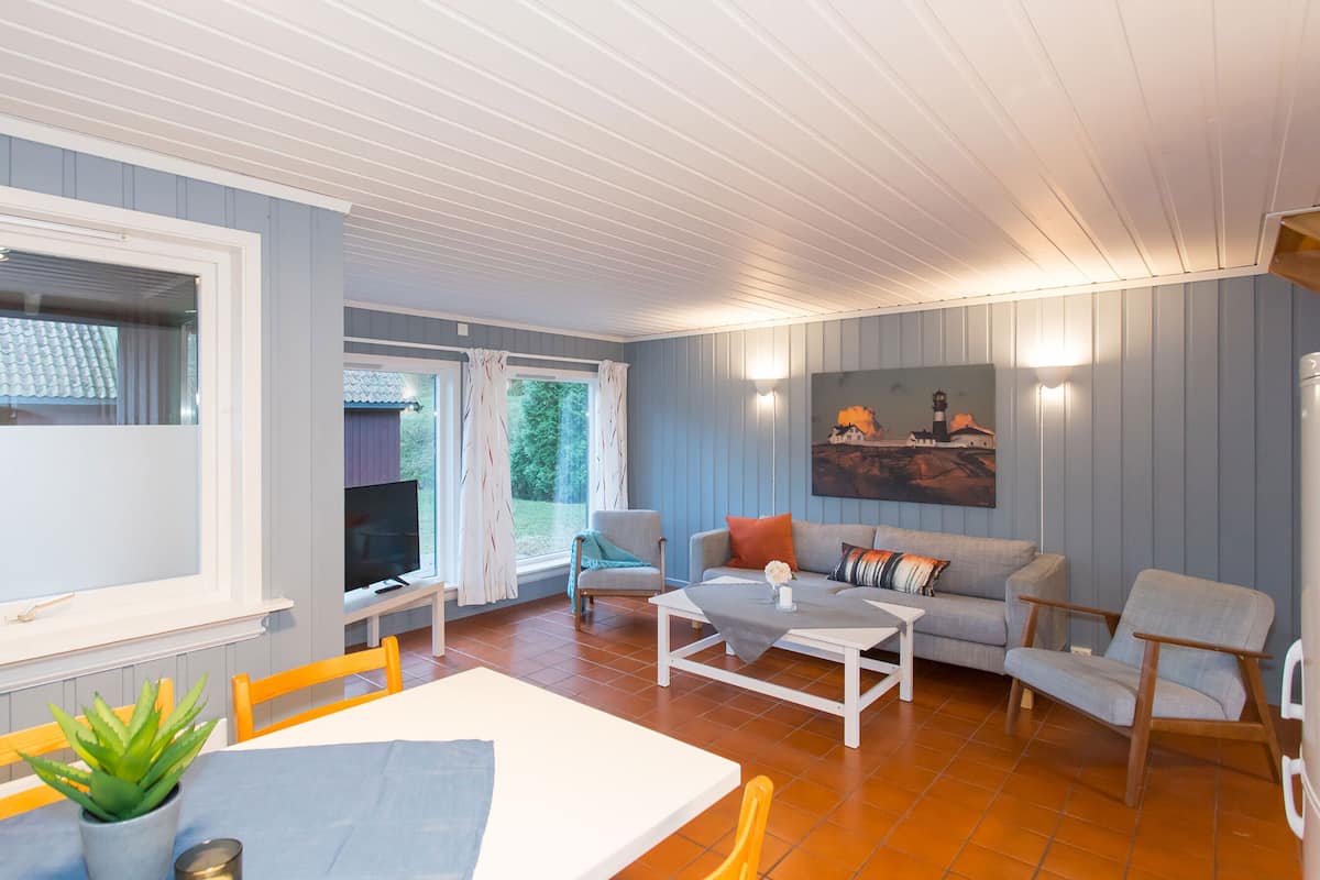 A cozy living room with a dining area, a sofa set, and a painting on the wall.