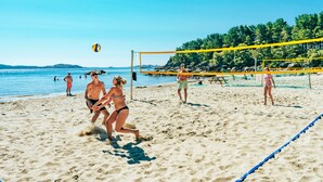 Un partido de voleibol de playa con red y jugadores en una arena.