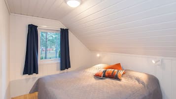 Ein Schlafzimmer mit Bett, Fenster mit Vorhängen und einer Deckenleuchte.