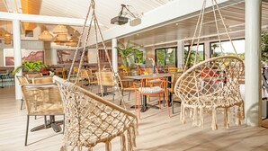 Un espacio interior amplio con sillas colgantes, mesas y sillas dispuestas para comer.