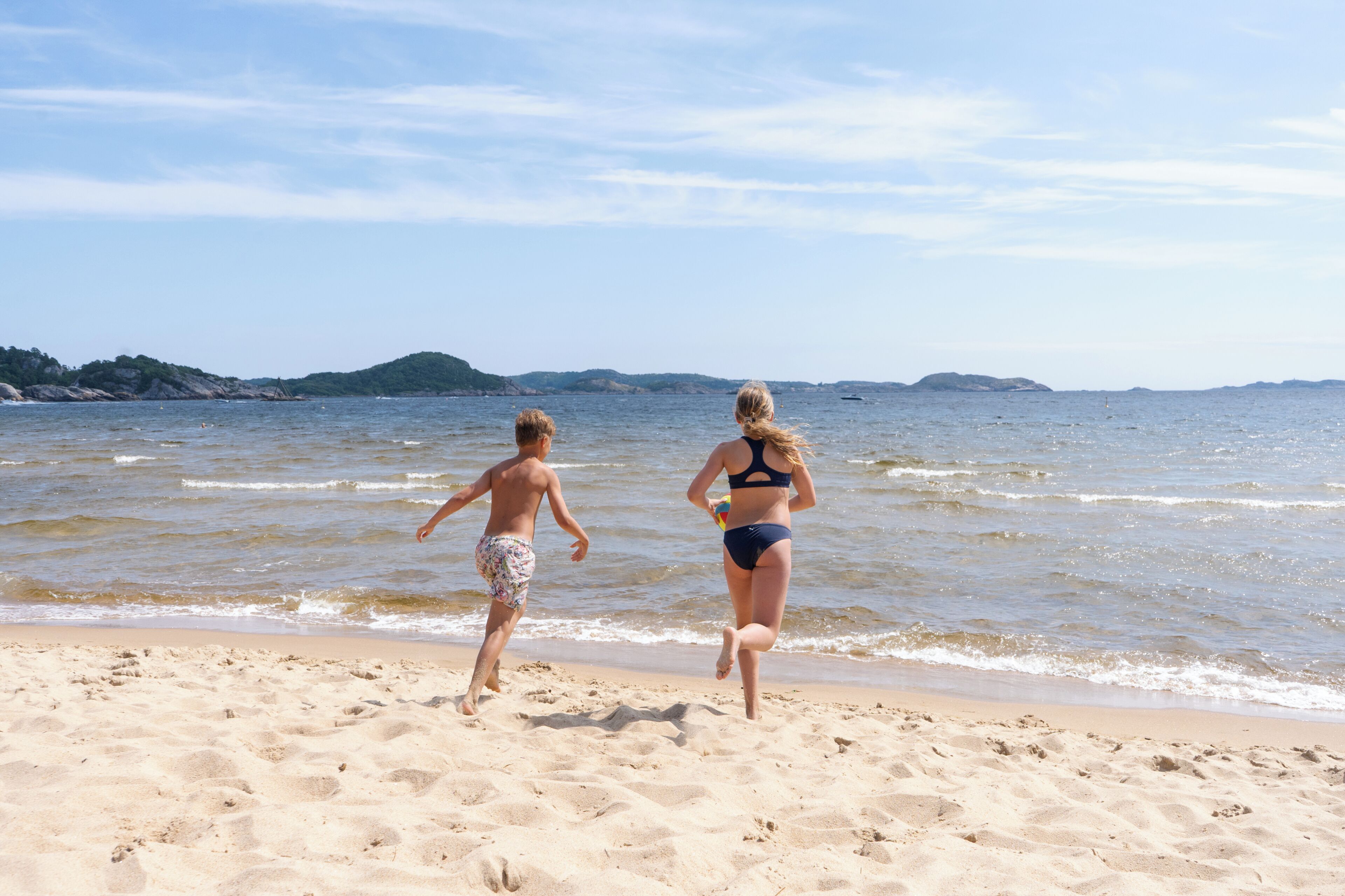 A beach with two people walking towards the water.