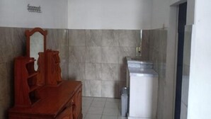 A bathroom with a wooden vanity, a mirror, a toilet, and a trash bin.