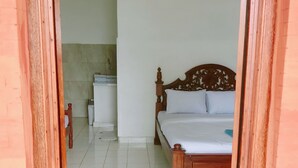 A bedroom with a wooden bed, white walls, and a tiled floor.