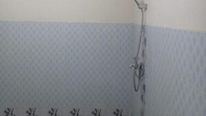A bathroom with a shower, a patterned wall, and a light fixture.