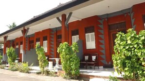 A building with a red facade, white overhang, and a series of windows with shutters.
