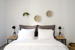A neatly made bed with white linens, two bedside tables with lamps, and decorative wall hangings.