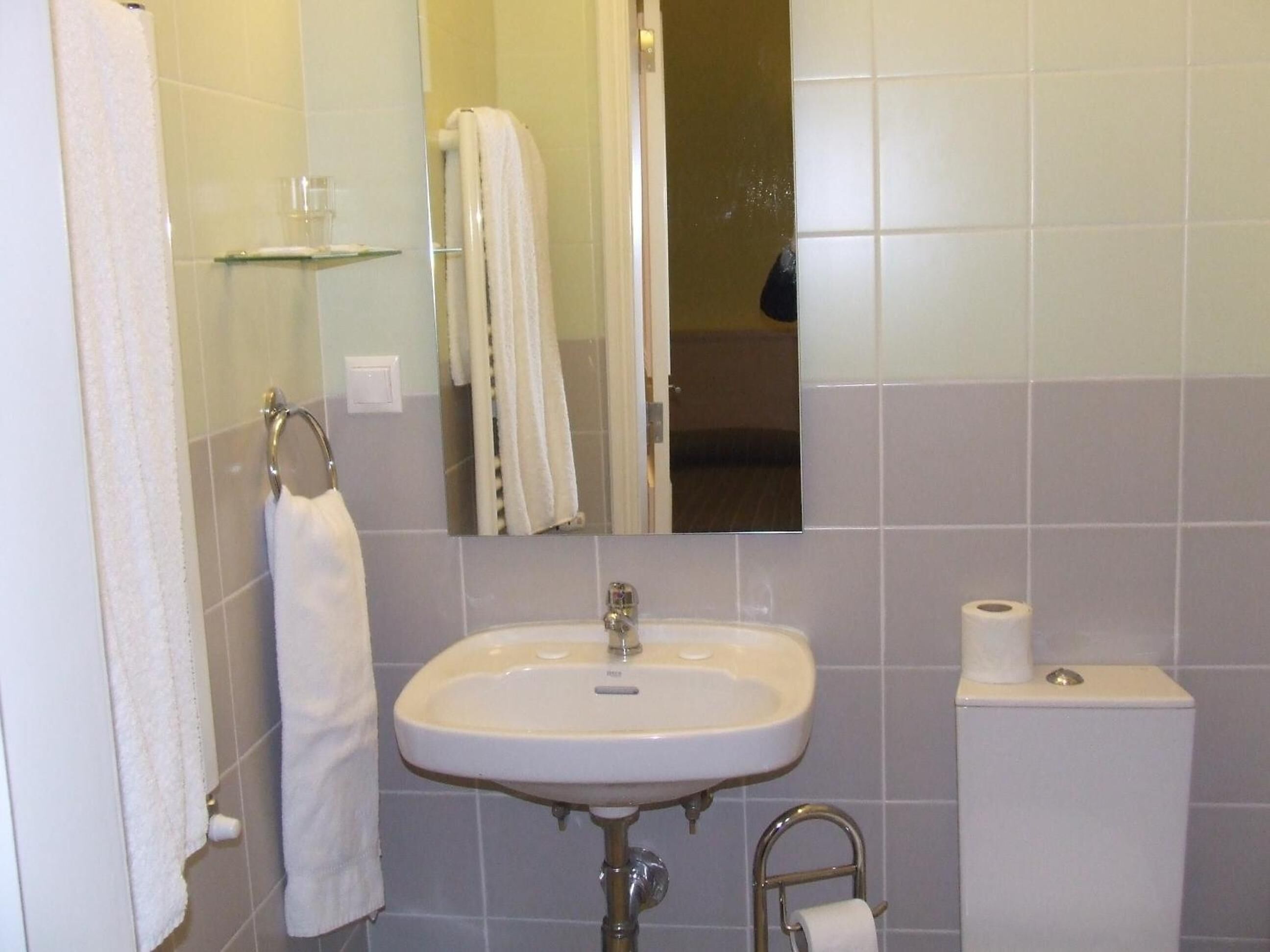 Une salle de bain avec un lavabo blanc, un miroir, un porte-serviettes et des toilettes.