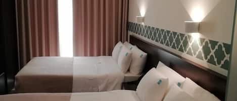 Una habitación de hotel con dos camas, una ventana con cortinas e iluminación en la pared.