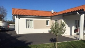 Una casa de un solo piso con techo de tejas rojas, un pequeño césped y una antena parabólica.