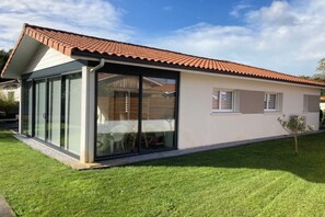 A modern house with a glass extension, a tiled roof, and a well-maintained lawn. - VILLA Biscarosse Ville - 6 pers. - 3 rooms (Biscarrosse)