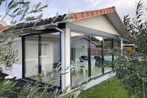 A modern house with a glass-enclosed patio, a tiled roof, and a well-maintained lawn. - VILLA Biscarosse Ville - 6 pers. - 3 rooms (Biscarrosse)