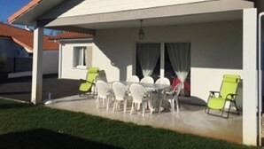 Un patio cubierto con una mesa, sillas, un ventanal y una puerta.