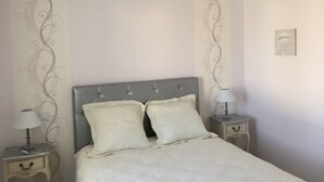 Un dormitorio con una cama, dos mesitas de noche, una lámpara y un diseño decorativo en la pared.