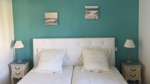 Una cama doble con cabecera blanca y dos mesitas de noche con lámparas.