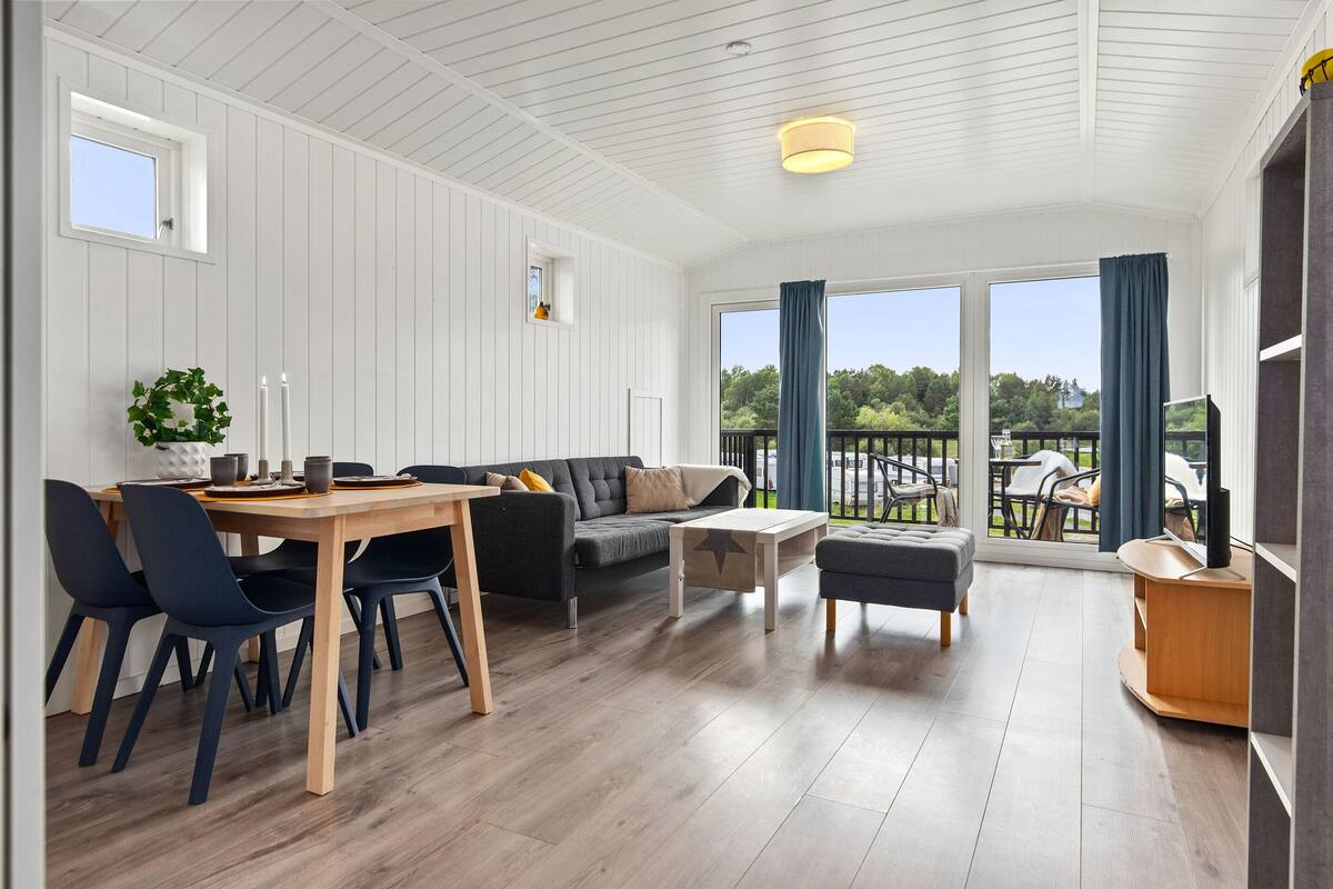 Een ruime kamer met een eethoek, een zithoek en een balkon met uitzicht.
