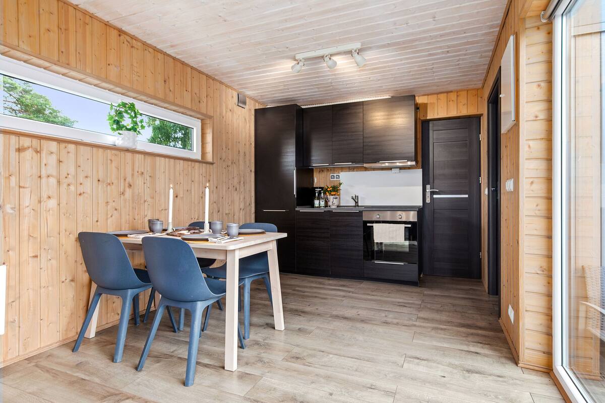 Een kleine keuken met donkere kastjes en een roestvrijstalen koelkast.