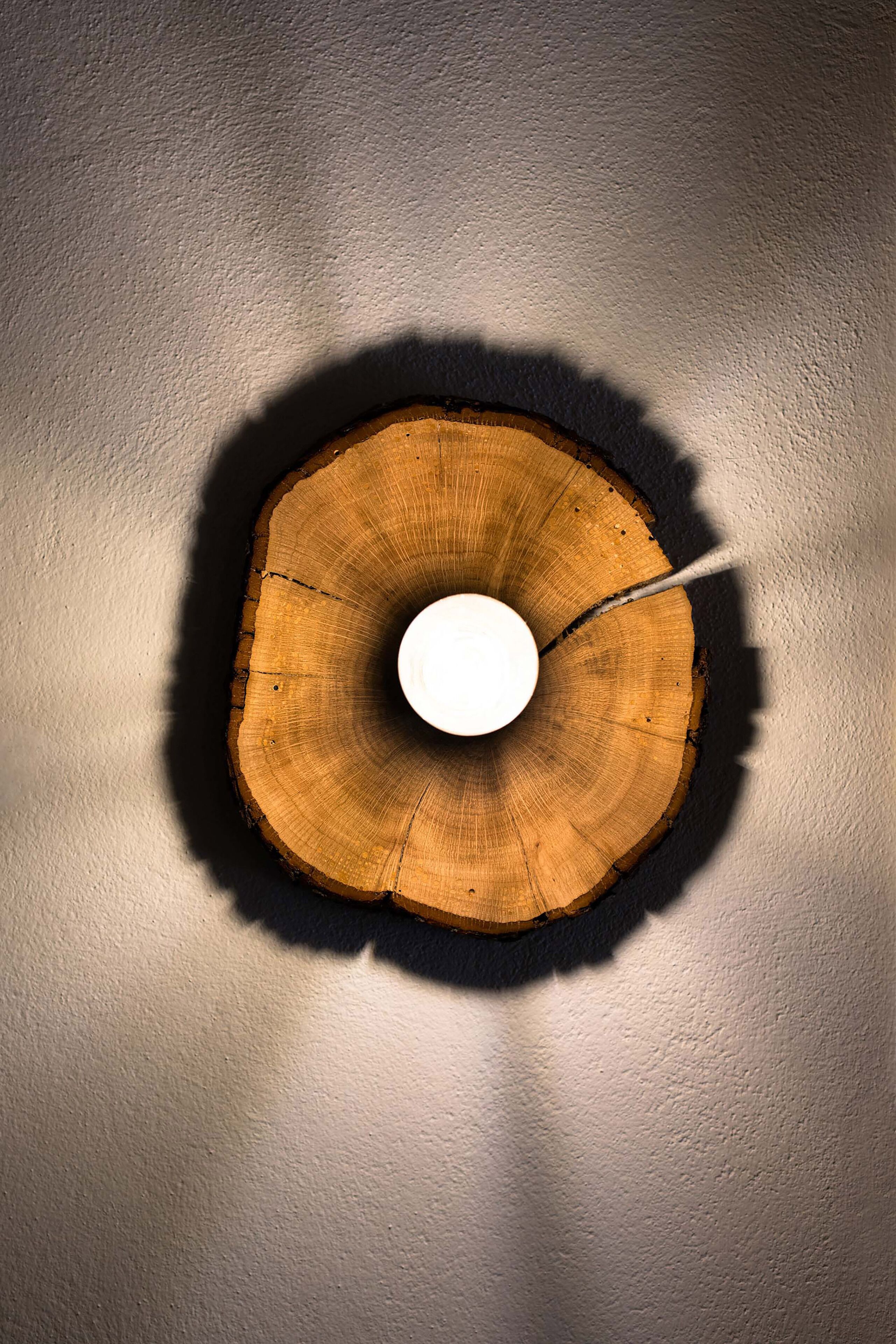 Un objeto circular de madera con un agujero en el centro, fijado a una pared con textura.