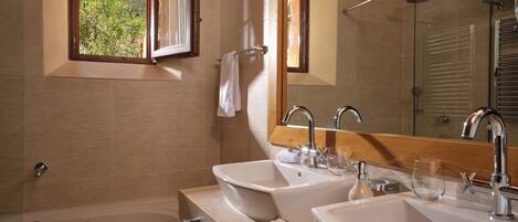 A bathroom with two sinks, a bathtub, and a window with an open shutter.