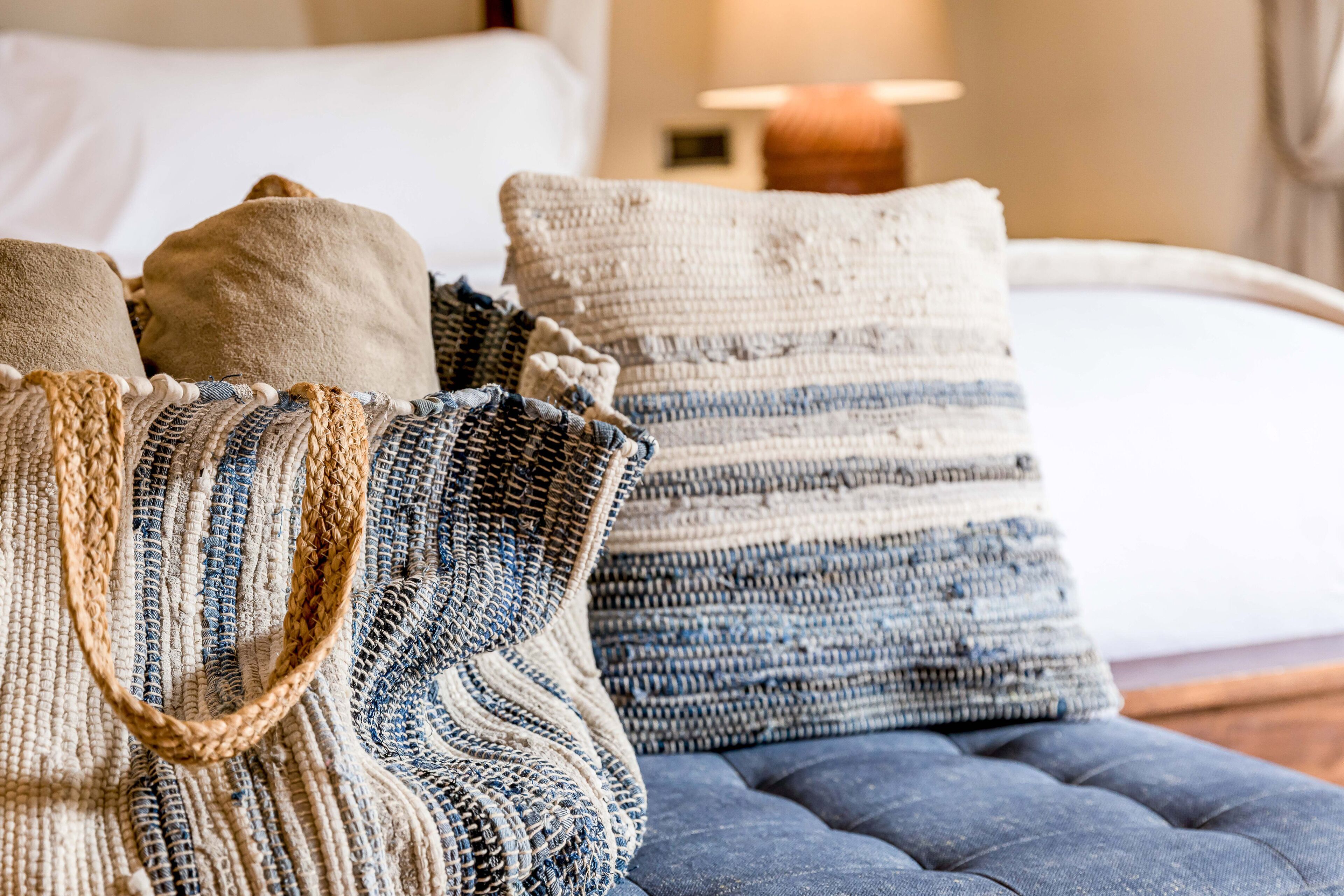 Cama com várias almofadas e cabeceira estofada.