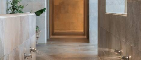 A modern bathroom with a pebble floor, a large mirror, and a wall-mounted shower.