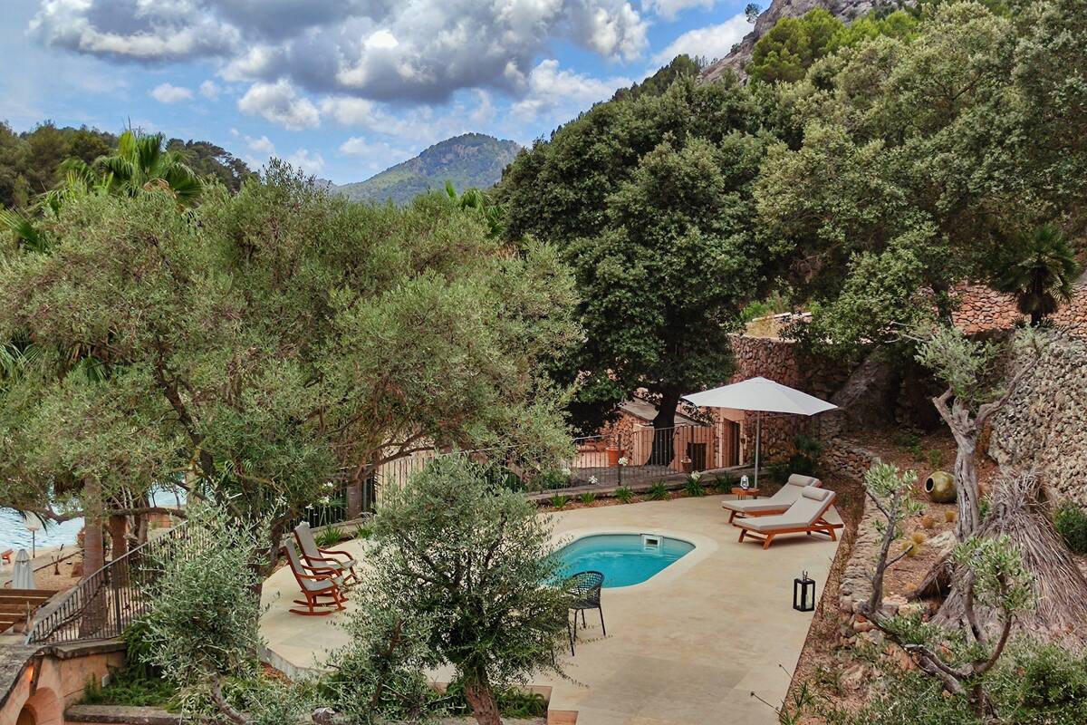A pool area with lounge chairs and a staircase leading to a terrace.