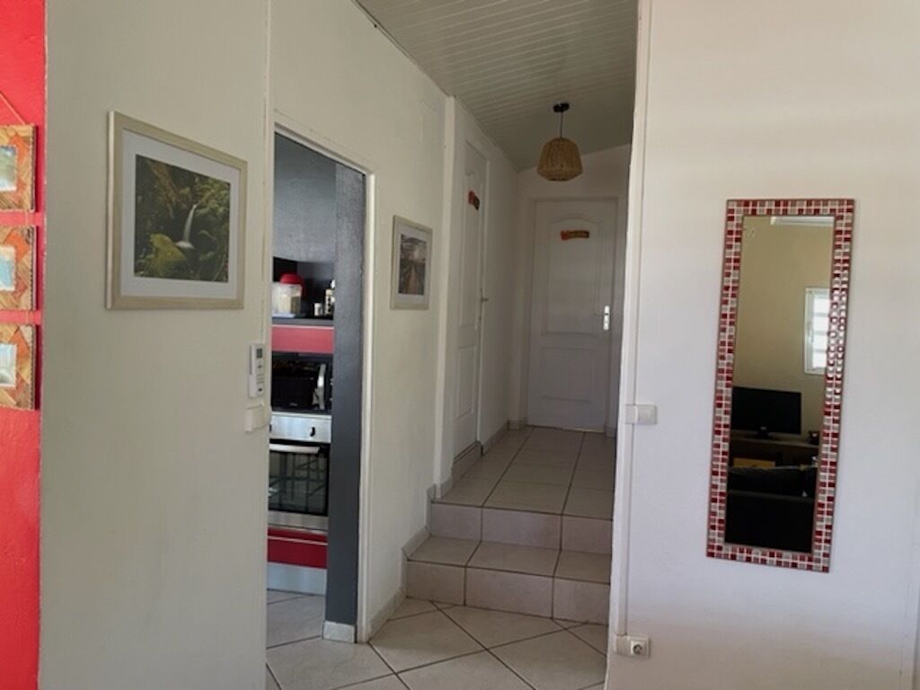Um corredor com piso ladrilhado, escada e espelho na parede.