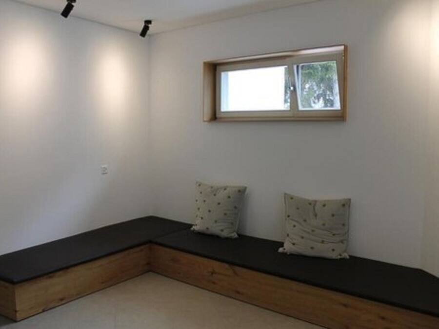 Ein Eckzimmer mit eingebautem Sitzplatz, einem Fenster und einer Deckenleuchte.