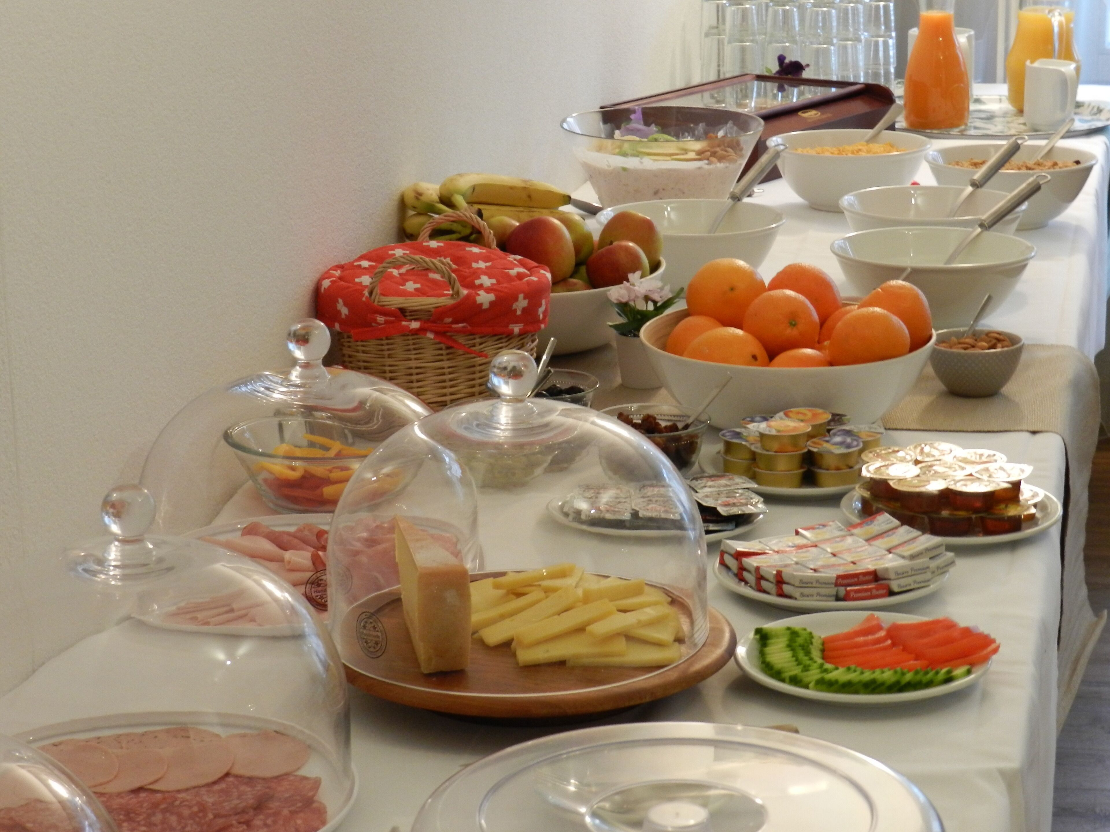 A buffet table with various food items including fruits, cheeses, and meats.