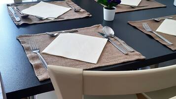 A dining table set with placemats, cutlery, and a small potted plant.