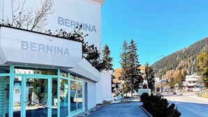 En bygning med navnet 'BERNINA' på facaden, med en moderne glasindgang og en klar himmel i baggrunden.