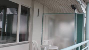 A balcony with a railing, a window, and a table with chairs.