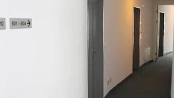 A corridor with doors labeled 601-604, a carpeted floor, and a light fixture on the ceiling.