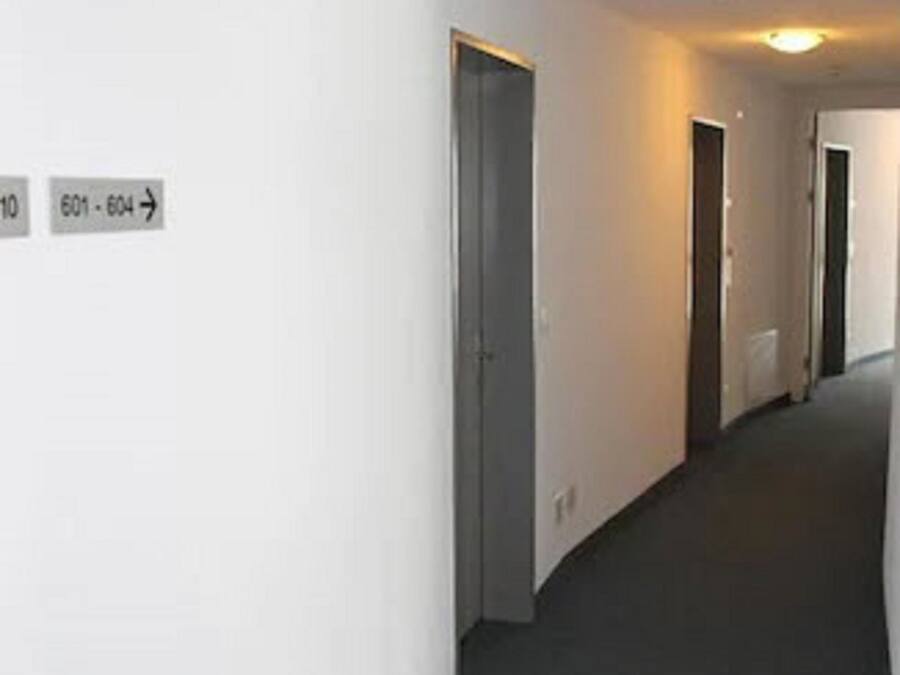 A corridor with doors labeled 601-604, a carpeted floor, and a light fixture on the ceiling.