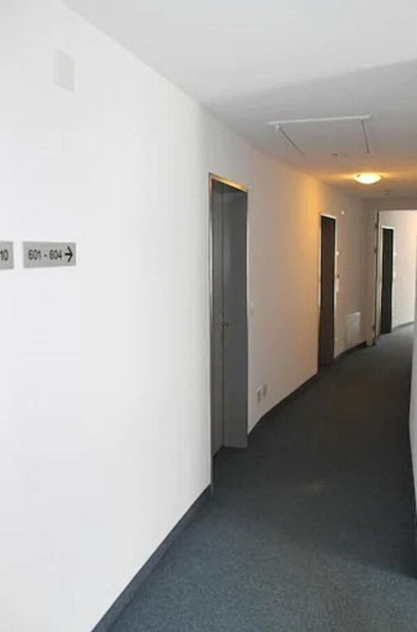 A corridor with doors labeled 601-604, a carpeted floor, and a light fixture on the ceiling.