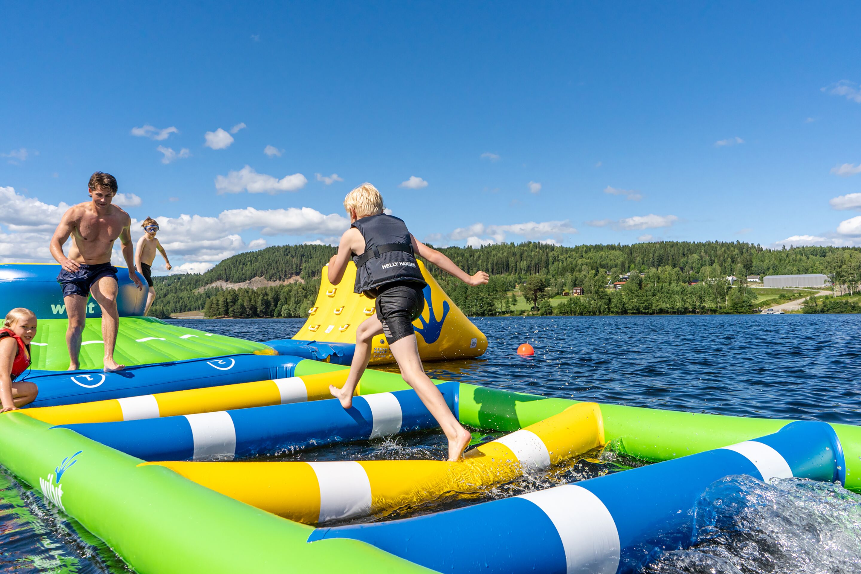 Un grupo de personas en una balsa inflable en un lago, con un paisaje boscoso al fondo.