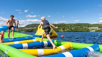 Un grupo de personas en una balsa inflable en un lago, con un paisaje boscoso al fondo.