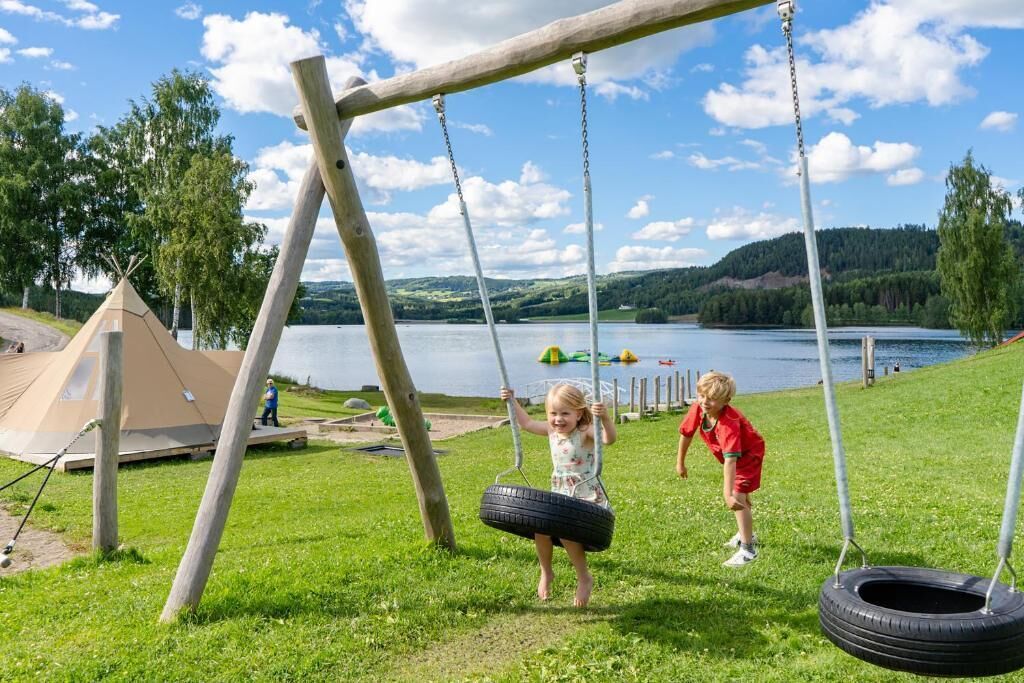 A grassy area with a swing set and a tent.