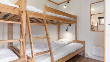 A bunk bed room with wooden frames, white bedding, and a small mirror on the wall.
