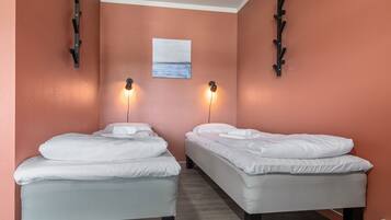 A room with two beds, a painting on the wall, and wall-mounted lights.