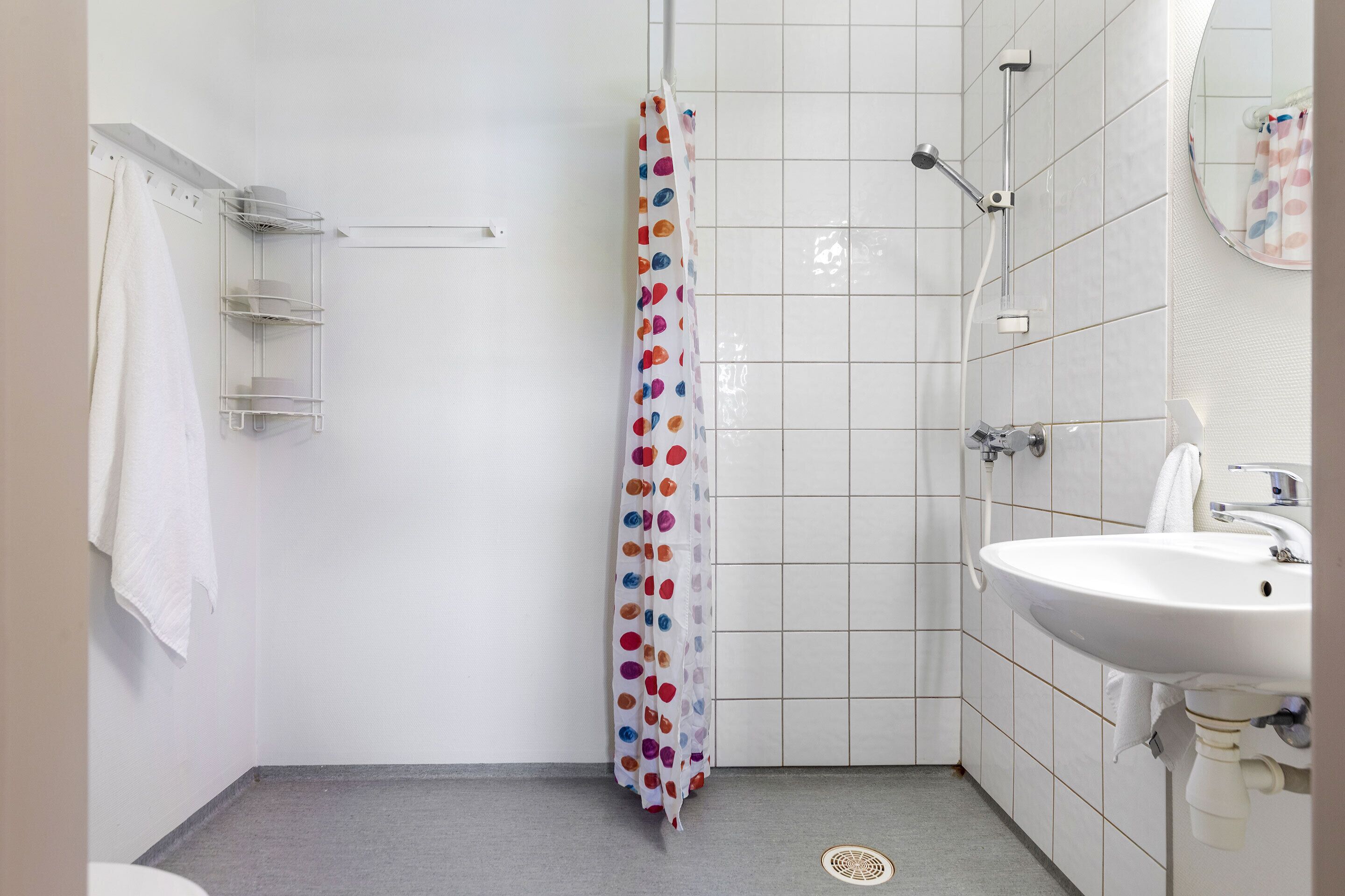 A bathroom with a shower, a sink, and a towel rack.