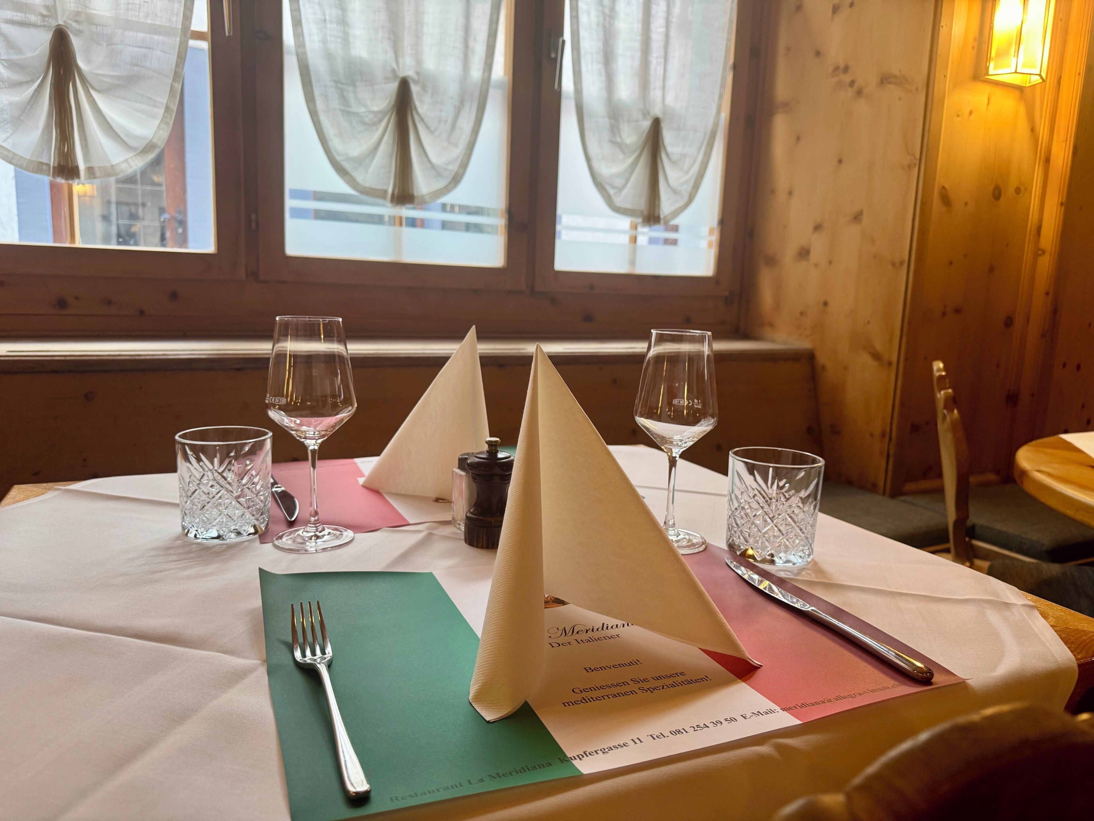 A table set for dining with a menu, glasses, and cutlery.
