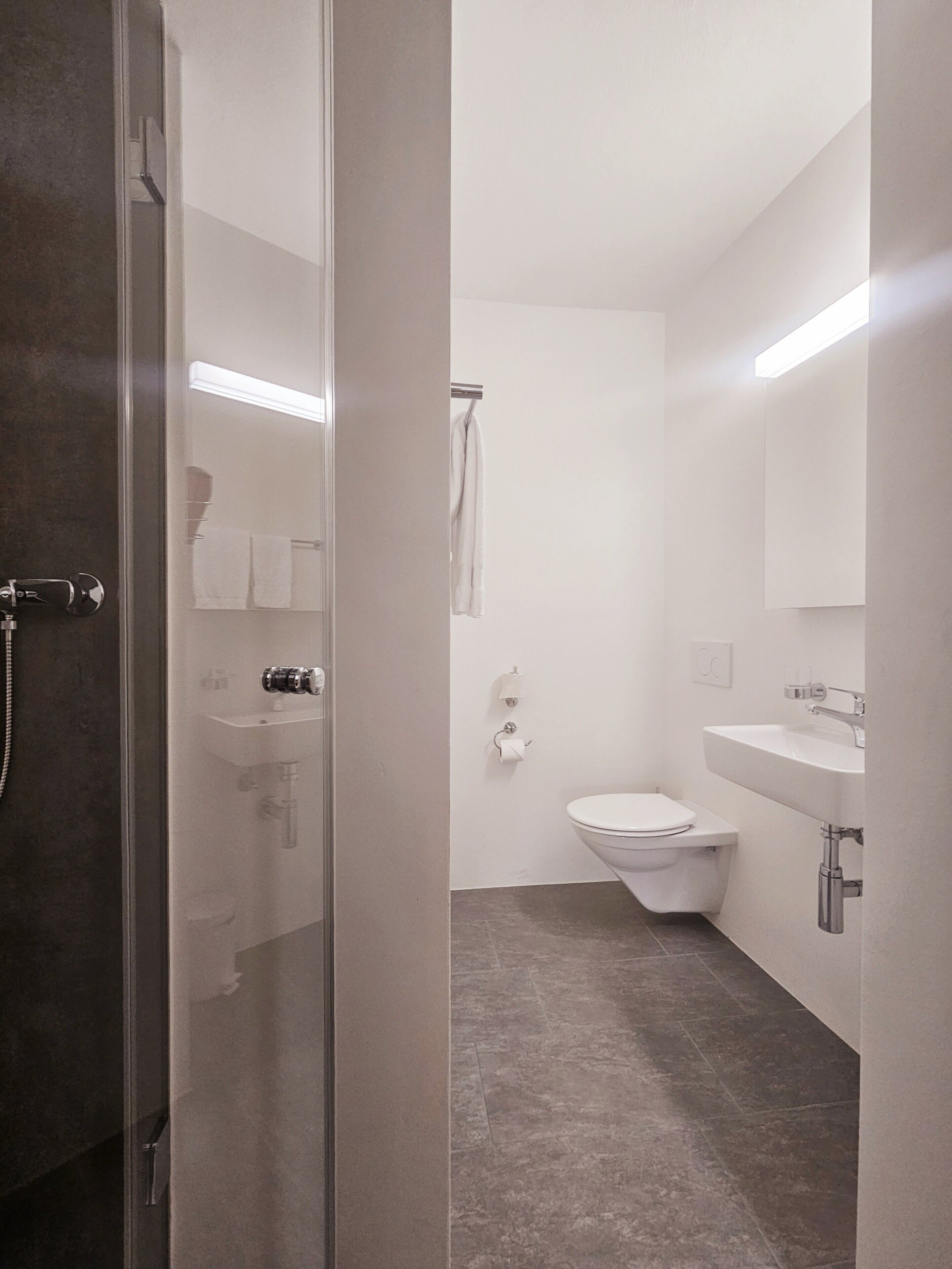 Une salle de bain moderne avec une douche à parois de verre, des toilettes, un lavabo et un porte-serviettes.