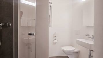 Une salle de bain moderne avec une douche à parois de verre, des toilettes, un lavabo et un porte-serviettes.