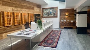 A modern interior with a wooden wall, a reception desk, a painting, and a patterned rug. - Hotel Alpenstadt (Chur)