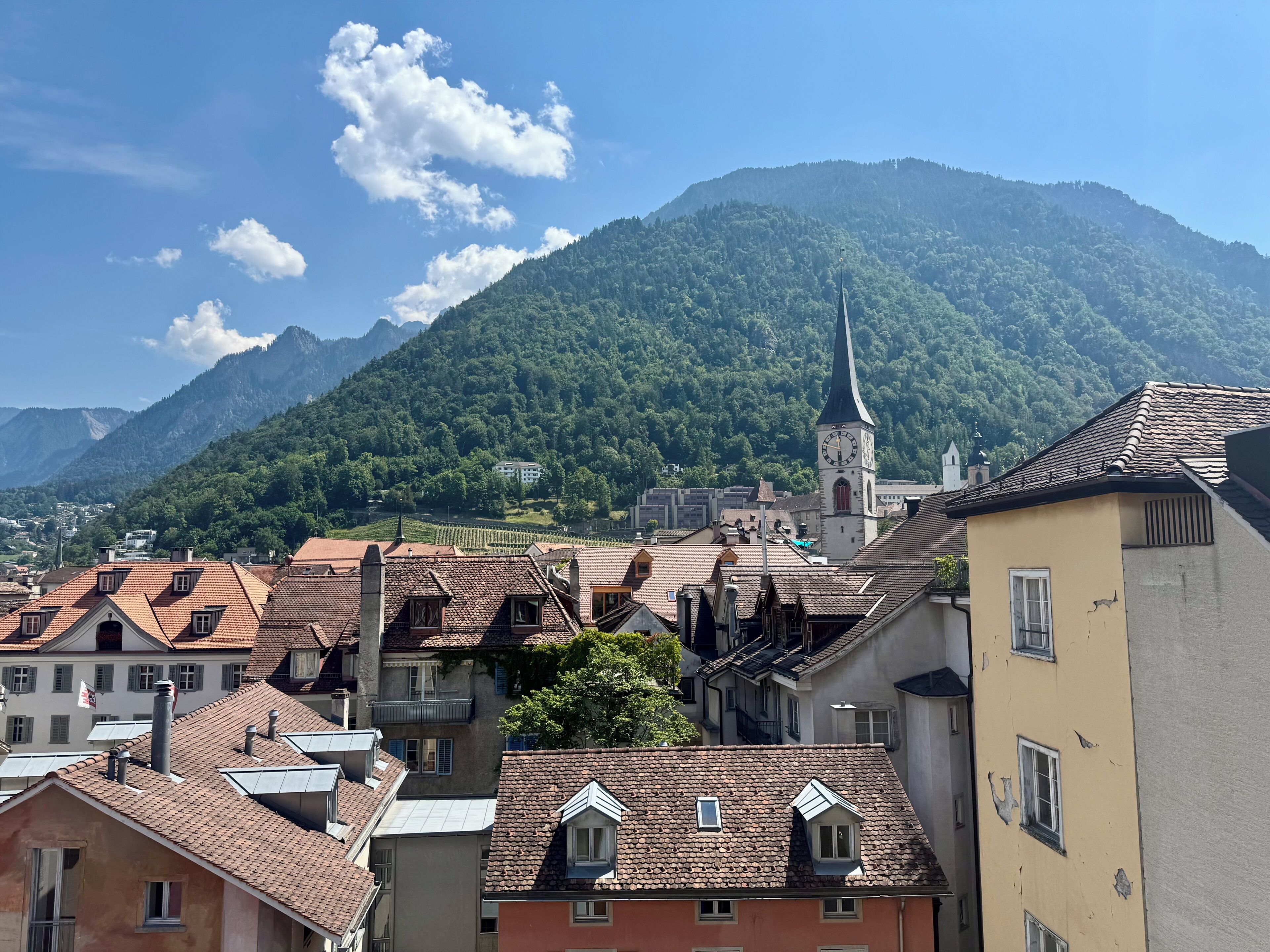 A town with buildings, a church, and mountains in the background.