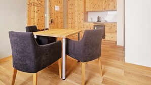 A modern kitchen with wooden cabinets and a dining area with a table and chairs. - Hotel Alpenstadt (Chur)