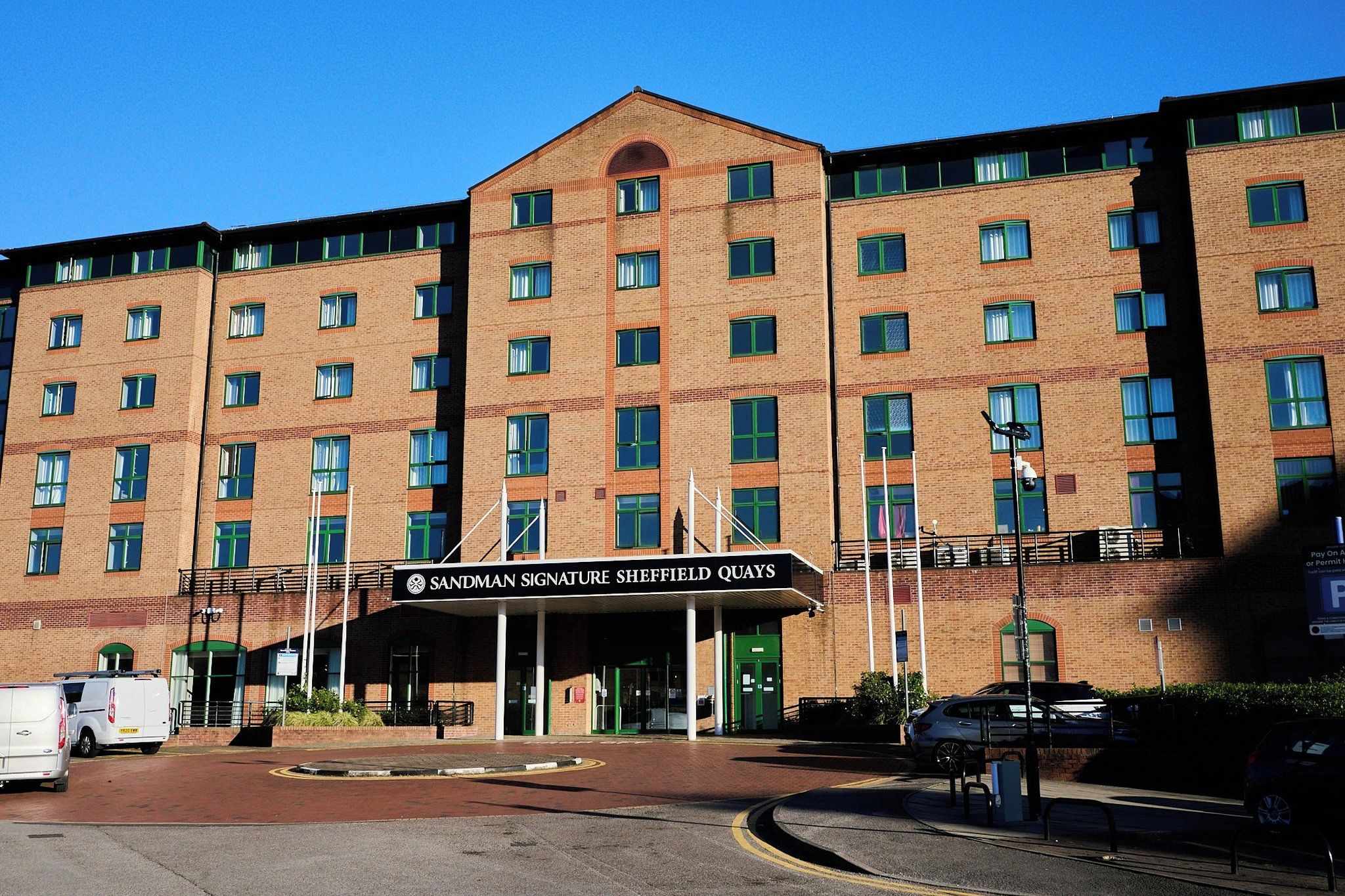 A multi-story hotel with a prominent entrance and a sign reading 'Sandman Signature Sheffield Quays'.