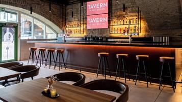 Una zona de bar con taburetes, una barra llena de botellas y un cartel que dice "TAVERN ON THE QUAYS".
