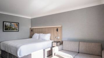 Una habitación de hotel moderna con una cama grande, un sofá y una mesita.