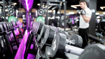 A gym with rows of dumbbells and a person exercising.